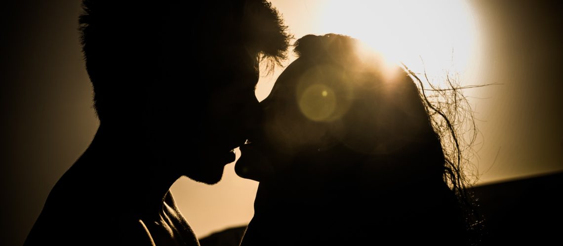 Silhouette Mann und Frau küssen sich vor Sonne