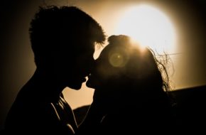 Silhouette Mann und Frau küssen sich vor Sonne