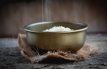 Reis wird in silberne Schüssel geschüttet