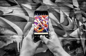 Smartphone wird vor bunte Graffiti Wand gehalten, sodass Streetart online animiert wird