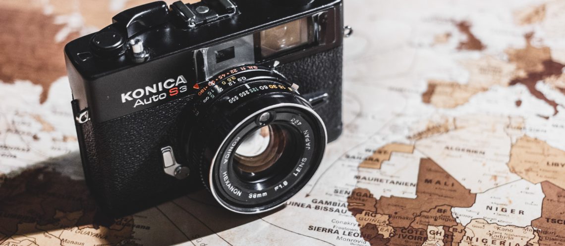 Weltkarte schwarze Kamera zum Artikelthema Reisefotografie: Ein Koffer macht Träume wahr