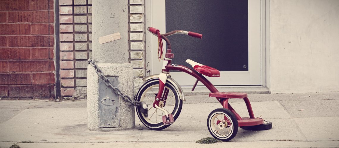 Kinder Dreirad an Laterne angeschlossen auf dem Bürgersteig zum Thema Berliner Kindheitsgeschichten