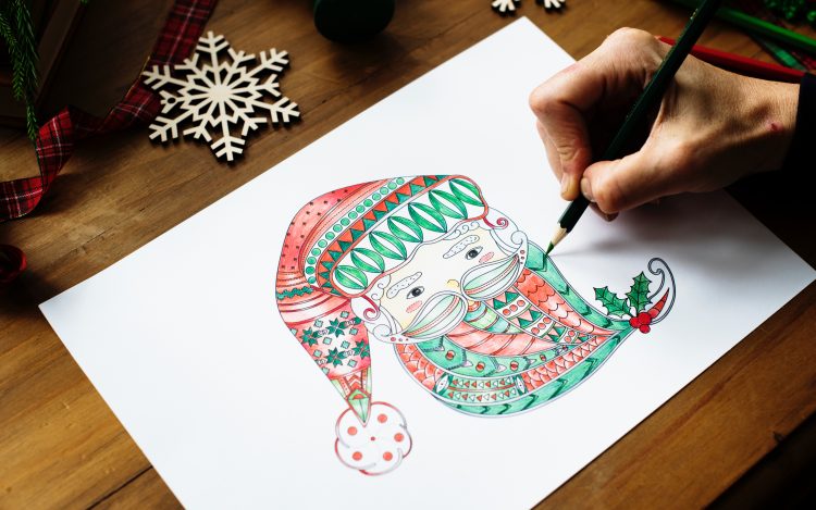 Holztisch Blatt Papier Bild vom Weihnachtsmann bunte Farben Schneeflocken Hand mit Stift zum Artikelthema Viraler Hit auf Twitter: Zweitklässler pfeift auf den Nikolaus